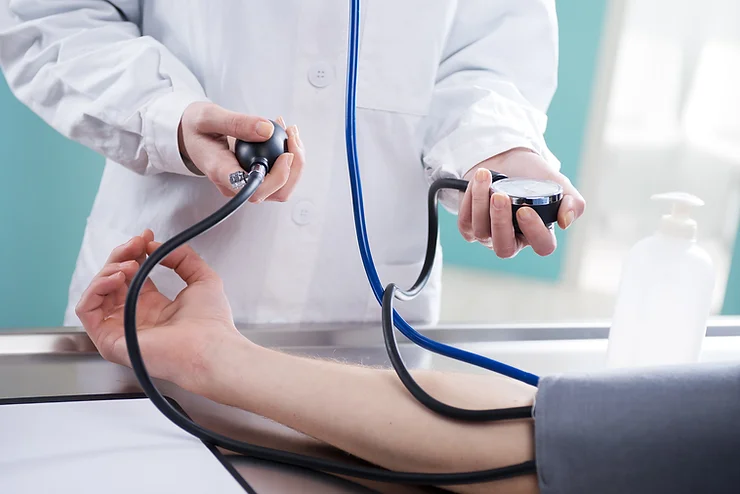 A healthcare professional checks a patient’s blood pressure using a sphygmomanometer in a medical setting.
