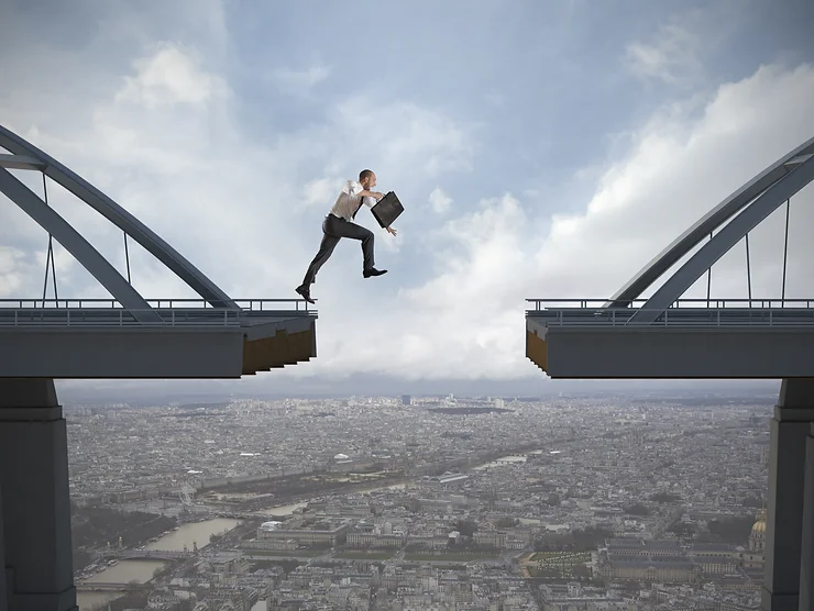 A man in business attire jumps across a gap in a bridge while holding a briefcase, with a cityscape visible below.