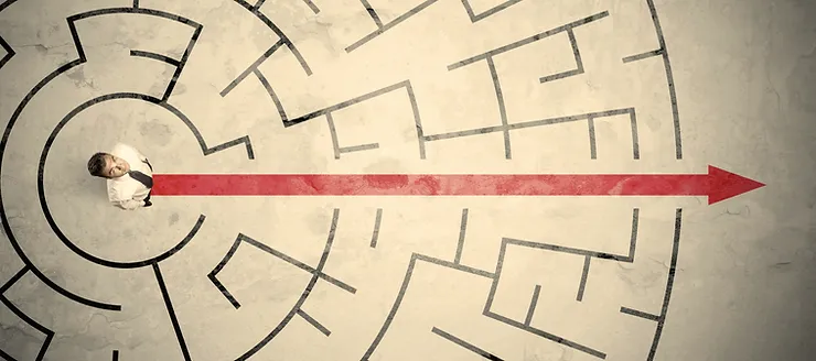 A person standing in a circular entrance of a maze, looking up. A red arrow points straight through the maze, indicating a direct path.