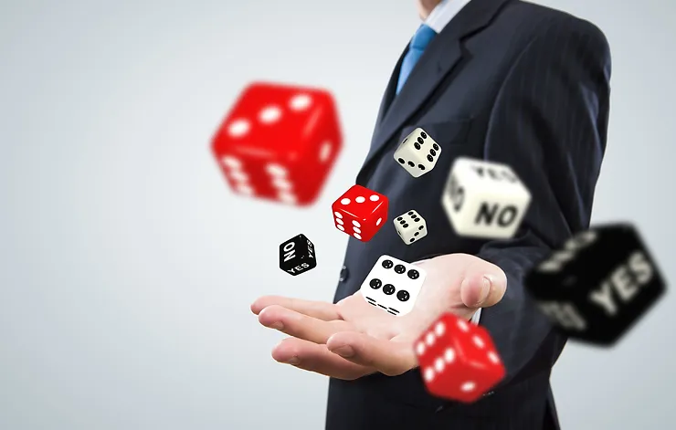 A person in a suit is holding out their hand, with multiple red, black, and white dice mid-air, some displaying "YES" or "NO," against a light grey background.