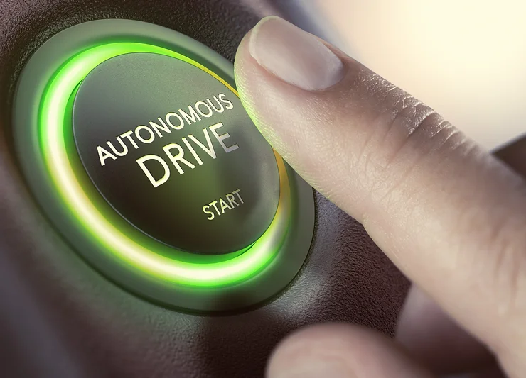 Close-up of a finger pressing a glowing button labeled "Autonomous Drive Start.