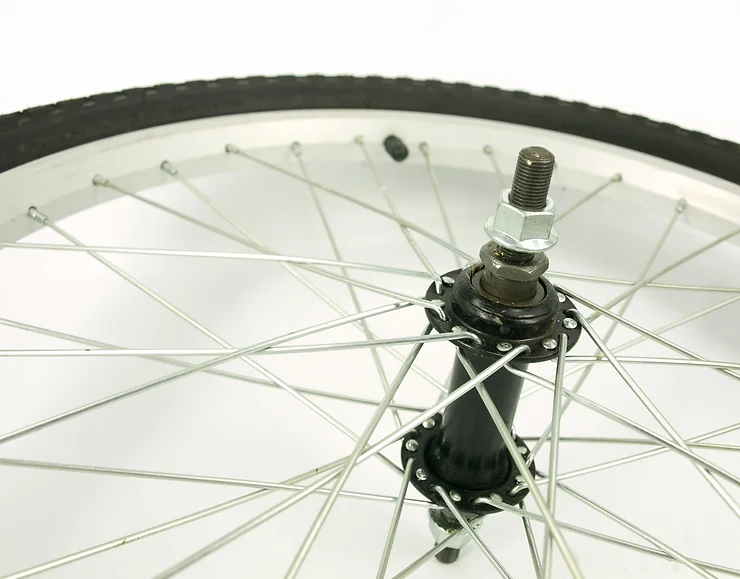 Close-up of a bicycle wheel showing metal spokes, a black hub, and a silver rim. The tire is partially visible, and the background is white.
