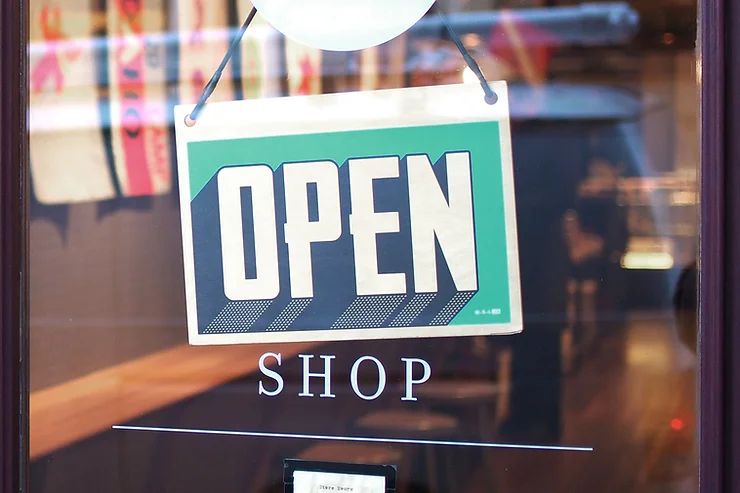 Storefront window with an "OPEN" sign hanging above the word "SHOP.