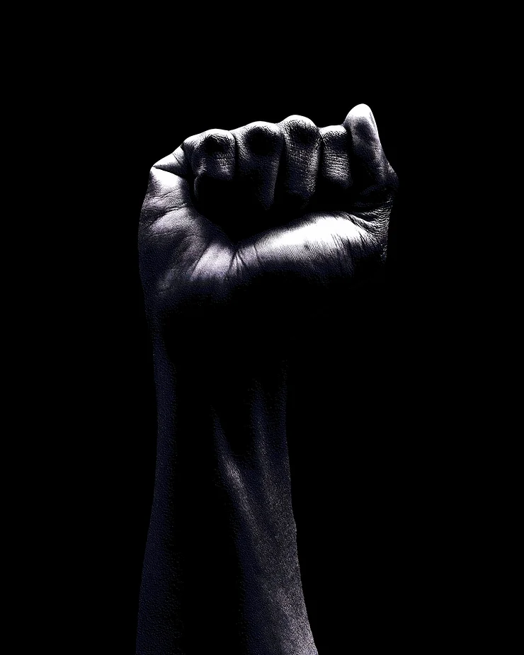 A clenched fist is raised against a black background, symbolizing strength and solidarity.